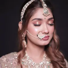 A close-up of a model wearing a full bridal jewellery set, including a maang tikka, nath, choker, and earrings. All pieces are available for rent.