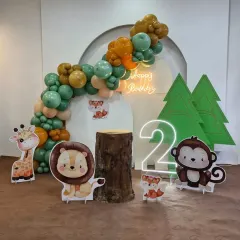 Our modern and cute jungle theme is perfect for a second birthday. This setup features pastel balloons, adorable animal cutouts, a rustic log prop, and a neon 'Happy Birthday' sign.