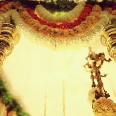 A detail shot of the hanging brass 'kumbah' elements. These traditional pieces add a touch of heritage and shine, perfectly complementing the colorful floral garlands in our desi decor setups.