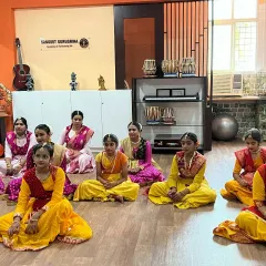 Students in colorful traditional attire sit attentively during their dance class. Discipline and respect for the art form are core values we instill in our students.