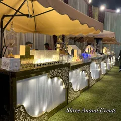 This is one of my charming outdoor beverage counters, set up under a canopy. The illuminated white and gold design features cute miniature house displays for juices, creating a whimsical and inviting look.