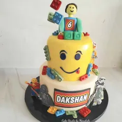 This two-tier Lego themed cake was a huge hit with Dakshan. It features a Lego head top tier and is decorated with edible Lego blocks and characters, using minimal fondant for a great taste.