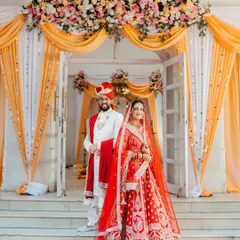 A classic portrait of the bride and groom, perfectly framed by the floral decor of their wedding hall. This is a timeless shot that captures the elegance and grandeur of a classic Indian wedding.