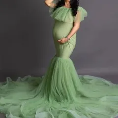 A studio shot of the light green mermaid gown against a solid grey background. This simple setup is perfect for clearly showcasing the dress's form-fitting silhouette and ruffled train.