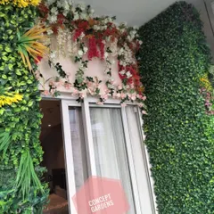 A beautiful detail from a balcony makeover, where we installed a cascade of artificial white and red flowers over the doorway. This adds a touch of color and softness, complementing the surrounding green walls.
