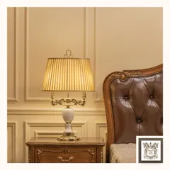 This classic table lamp features a beautiful white marble-like base with ornate gold accents and a pleated fabric shade. It's a sophisticated piece that adds a touch of regal elegance to a bedside table.