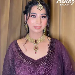 A full-face view of this elegant party makeup. The client is wearing a beautiful purple suit with traditional jewelry, and the makeup enhances her features without overpowering them.
