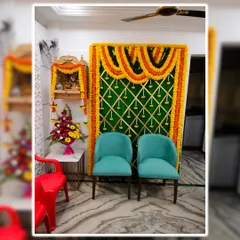 This is a budget friendly decoration we did for a home pooja. It features a traditional marigold backdrop next to the home mandir, with chairs for seating, creating a functional and festive corner.