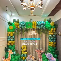 We brought the jungle to life for this 2nd birthday party. This setup includes a full balloon arch with green, gold, and teal chrome balloons, jungle leaf accents, and life-sized cutouts of a giraffe, deer, and elephant.