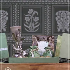This hamper showcases the beauty of simplicity and elegance. The olive green velvet potlis, a custom card, and a silver-plated decorative piece come together to create a gift of understated luxury.