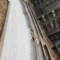 After the drainage cells, we lay down a geotextile filter fabric. This white sheet prevents soil from clogging the drainage system while allowing water to pass through freely.