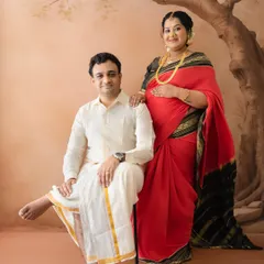 A poised and elegant couple's portrait. The mom-to-be stands gracefully while her partner is seated, both in traditional attire, creating a balanced and regal composition.