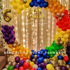 This circular balloon arch uses a rainbow of colors to create a vibrant and cheerful photo spot for a 6th birthday party. Set against a curtain of fairy lights, this decoration is perfect for adding a pop of color and fun to any celebration.