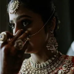 A quiet moment of reflection for the bride before the ceremony begins. The close-up on her face, with the nath being adjusted, is intimate and emotional.
