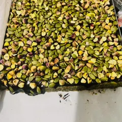 A close-up of my Pumpkin Seeds & Fig bars before they are cut. You can see the dense layer of pumpkin seeds and pistachios over a rich, dark base made from figs and nuts.