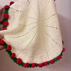 A view of the blanket being held, showing its texture and the intricate stitch work that creates the spiderweb-like pattern in the center.