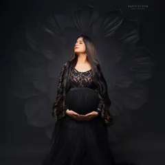 A powerful and elegant solo portrait. We use dramatic studio lighting and a classic black gown to sculpt the beautiful silhouette of the baby bump, creating a timeless piece of art.