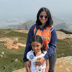 A mother and her young daughter on a 'Mom & Me' trek, with a vast landscape behind them. These hikes are designed to be accessible and enjoyable for young children.