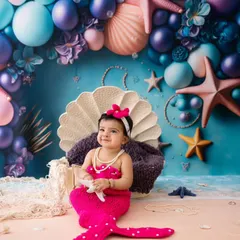 Look at this adorable little mermaid. This photo shows the fun and creativity of my fantasy-themed shoots, complete with a colorful under-the-sea backdrop and a custom mermaid tail outfit.