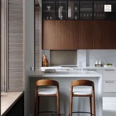 A closer look at the breakfast bar area, featuring comfortable wooden stools and louvered window shutters that add a touch of classic charm to the contemporary space.