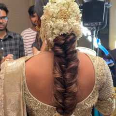 A back view of the South Indian bridal braid, captured on set. This angle shows the full length of the braid and the dense floral arrangement at the base, a hallmark of traditional South Indian hairstyling.