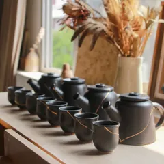 A set of four teapots and matching cups, each with a delicate gold line. These were part of my experiments to solve airflow and pressure issues to achieve a perfect pour.