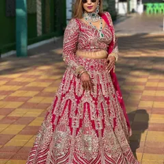 Make a grand statement with this heavily embroidered magenta bridal lehenga. The intricate silver work covers the entire skirt and full-sleeve blouse, creating a look of pure opulence. This is a perfect rental for a bride who wants all eyes on her.