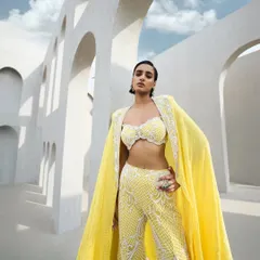 A breathtaking sharara set, fully embroidered like a tapestry woven from light. Paired with a flowing cape, this ensemble is a dance of radiance and grace.