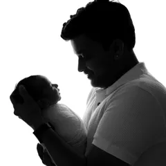 A powerful black and white silhouette of a father looking down at the newborn baby he is holding.