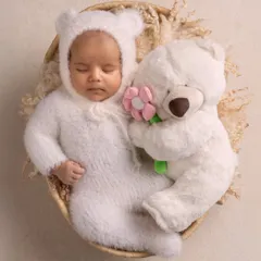 A sweet, sleeping newborn dressed as a tiny bear, cuddling with a teddy. This artistic portrait shows how we can use simple props to create a magical and adorable scene.