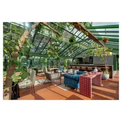 Another view of the conservatory, showing how the space integrates with nature. A tree grows through the room, enhancing the connection to the outdoors and complementing the curated furniture and decor.