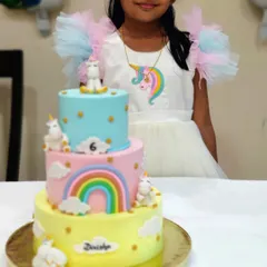 A close-up of our daughter and her custom three-tier unicorn birthday cake. We loved bringing her vision to life with pastel colors and cute, handmade unicorns.
