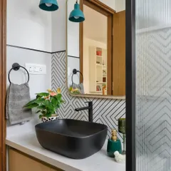 A playful bathroom in 'House of Kismish' with bold geometric tiles, a black vessel sink, and turquoise pendant lights. This space proves that bathrooms can be fun and full of personality.