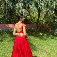 The back view of this red crop top reveals a modern, deep backless design, adding a touch of unexpected elegance to a traditional ensemble.