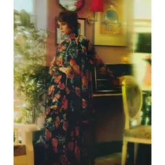 From 'Chapter 1: The Wait'. The model stands in a room filled with lush plants, wearing a flowing floral gown. The styling here establishes the theme of romantic nostalgia, a world steeped in memory.