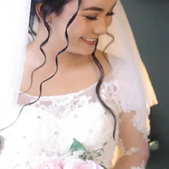 A beautiful, candid shot of the bride smiling. The soft curls framing her face and the delicate makeup create a look that is both romantic and effortlessly chic.