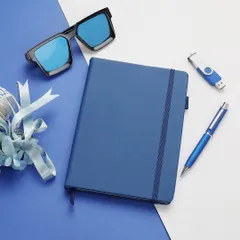A stylized flat-lay of a blue corporate gift set, including a notebook, pen, and sunglasses, composed on a two-tone background for a modern, graphic look.