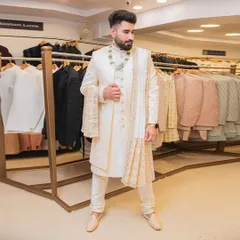 For the groom who wants a timeless and royal look. This classic ivory sherwani features delicate gold embroidery, a matching stole, and elegant accessories. We help you get the complete dulha look for your big day.