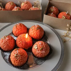 A plate of my motichoor ladoo candles, one of them lit to show it in action. They look incredibly realistic and are always a conversation starter.