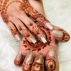 Another angle of these beautiful bridal nails. You can see how the gold glitter catches the light, making the detailed henna work on her hands and palm stand out even more.