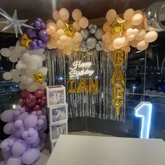 A similar "Baby" shower or first birthday setup, showing the 'BABY' blocks and marquee number '1' against a silver fringe curtain.