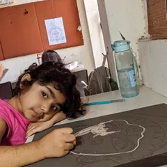 A quiet moment of concentration. Here, a student is carefully outlining her drawing, getting the composition just right before adding color.