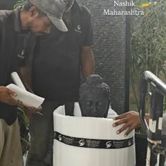 The careful process of wrapping a black marble Buddha head in protective foam before it is placed in its custom shipping crate.