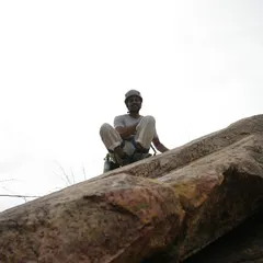 A happy climber at the top of a route, taking a well-deserved rest and enjoying the view. This is the feeling of accomplishment we all chase.