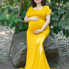 Basking in the warmth of the sun and new life. This mom-to-be in a stunning yellow gown is the picture of serenity, surrounded by the lush green of the park.