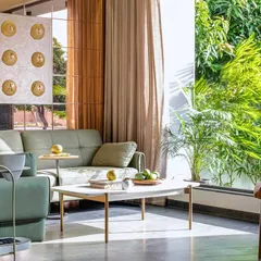 Here, you can see how the large window in the living room of Tranquil Mango Haven frames the vibrant green foliage outside. I design every view with intent, making the garden feel like a living piece of art that is part of the interior decor.