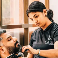 A sharp beard is just as important as a good haircut. Here, one of my expert stylists is carefully trimming and shaping a client's beard. I ensure we pay close attention to the lines and details for a clean, professional look.
