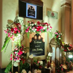 A personalized welcome for a 50th birthday celebration with a Sufi Night theme. The entrance features a custom sign, ornate Moroccan-style lanterns, and beautiful arrangements of red and pink roses.