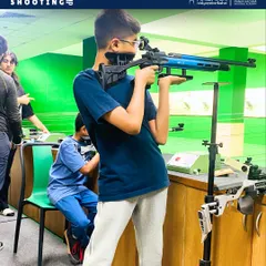 A young shooter focuses on his target during a summer camp session. We provide age-appropriate equipment and a supportive environment to help children develop their concentration and skills.