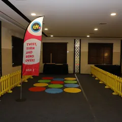 We set up various game zones, including this floor game of "Twist, Turn and Bend Over," complete with branded flags and safety barricades for organized fun.